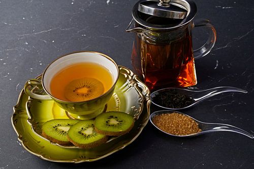 Black tea with kiwi in a cup, teapot, sliced kiwi