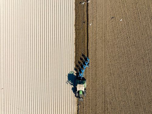 Tracteur préparant le sol pour la plantation de cultures, vu d'en haut.