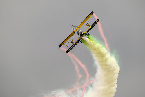 Yellow biplane with colourful smoke