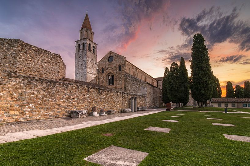 The sun rises behind the Basilica of Aquileia, illuminating the clouds present by Bram Lubbers