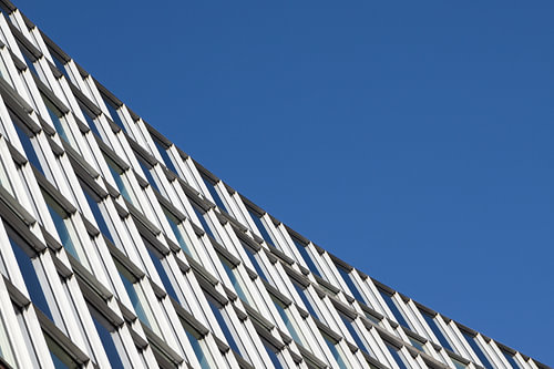 moderne Architektur, Fensterfassade des städtischen Gebäudes diagonal gegen den blauen Himmel mit Ko