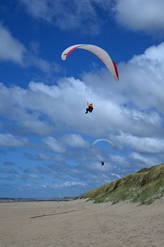 Paragliders zweven over het duin