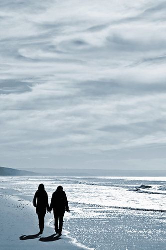 Lesbisches Paar. Silhouette von zwei Frauen zu Fuß Seite an Seite an der Wasserlinie auf einem ruhigen Strand