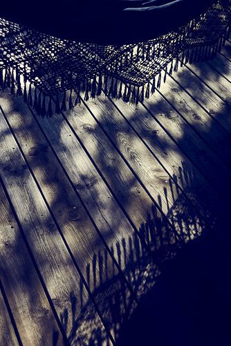 Detail van een hangmat met franjes in het avondlicht op het terras