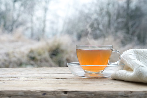 Heißer Tee auf einem rustikalen Holztisch im Freien an einem kalten Wintermorgen, Kopierraum, gewähl