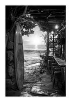 Surfboard leaning against a beach hut at sunset