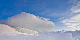 Eine Eisscholle, ein Buckel von bläulich-rosa Farbe gegen einen blauen Himmel ragt auf dem Baikalsee von Michael Semenov