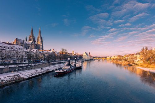Skyline von Regensburg mit Dom und Steinerner Brücke im goldenen Morgenlicht im Winter mit Schnee