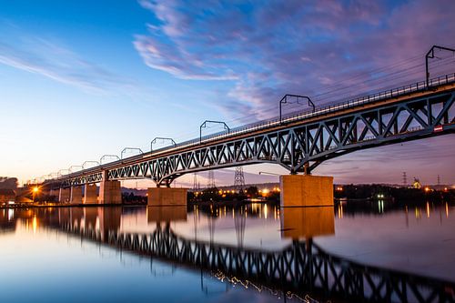 Treinbrug visé bij de Maas rivier - zonsondergang met spiegeling blauwe lucht bij spoorbrug
