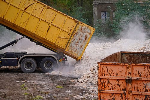 Vrachtwagen op een bouwplaats dumpt een container met stenen