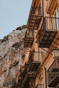 Antike Gebäude mit Balkonen in Cefalu Stadt unter den Felsen, Sizilien Italien. von Manon Visser