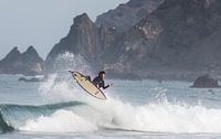 Surfer flying with cliff beackground