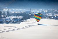 Heißluftballons schmücken den Himmel über dem verschneiten Inzell in Deutschland