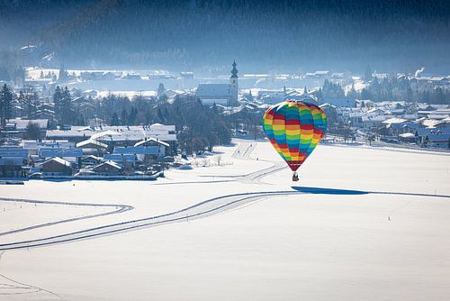 Heteluchtballonnen sieren de lucht boven een besneeuwd Inzell in Duitsland