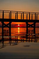 Zonsondergang onder de pier met reflecties in Lago di Lèsina