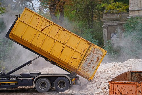 Vrachtwagen op een bouwplaats dumpt een container met stenen