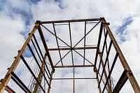 Urbex - verroeste metalen constructie tegen een blauwe lucht met wolken