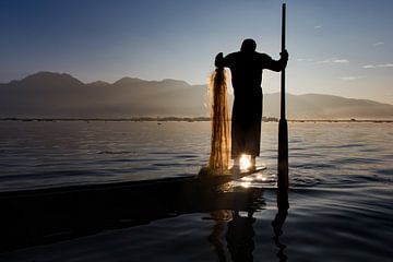 FISHERMAN AT SUNRISE vist ON TRADITIONAL WAY TO INLE LAKE IN MYANMAR. With a basket the fish is caug by Wout Kok