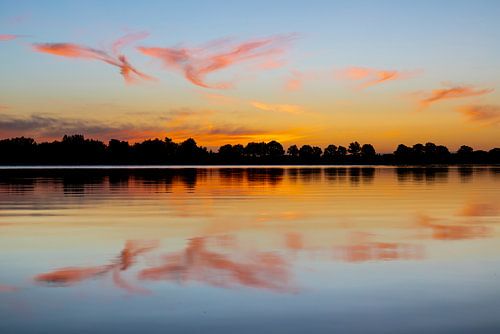 Een landschap van rode  wolken die reflecteren in het water, ochtendrood