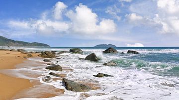 Sunny tropical beach with rocks in a strong surf  by Tony Vingerhoets