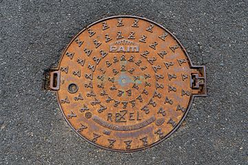 Runder Gusseisen-Schachtdeckel in Asphalt von MMFoto