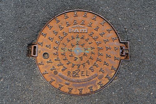 Rond gietijzeren putdeksel in asfalt