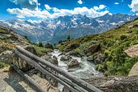 Brug over smeltwater, met uitzicht op de bergen boven Saas Fee
