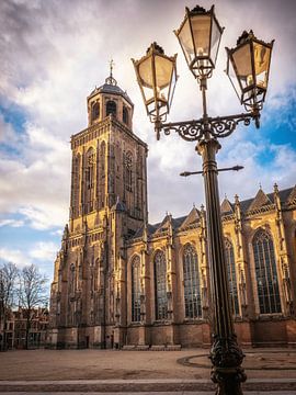 Lamp post in front of the Lebuinus church with clouds over the tower and sun in Deventer by Bart Ros