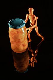 Canned fruit with wooden doll and black background by Hans-Jürgen Janda
