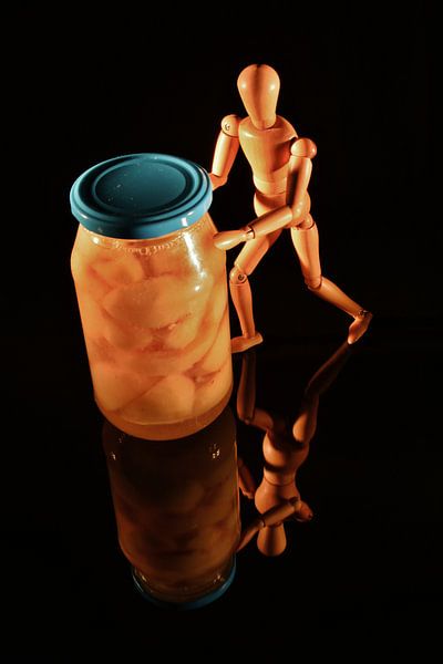Obstkonserven mit Holzpuppe und schwarzem Hintergrund von Hans-Jürgen Janda