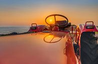 Sunset through the wheel of a tractor by Harrie Muis thumbnail