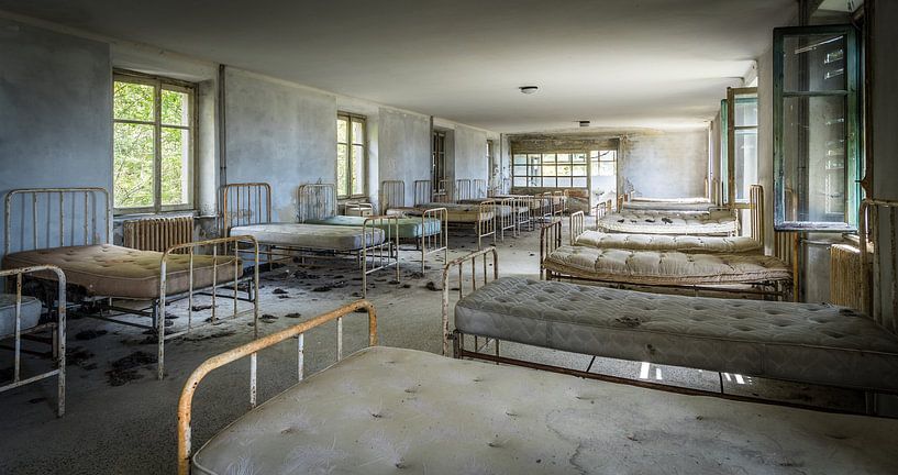 Beds in an abandoned hospital by Inge van den Brande