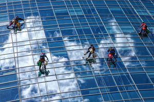 Glasreiniger hängen an einem Seil, während sie die Fenster eines gläsernen Wolkenkratzers in Buenos  von Wout Kok