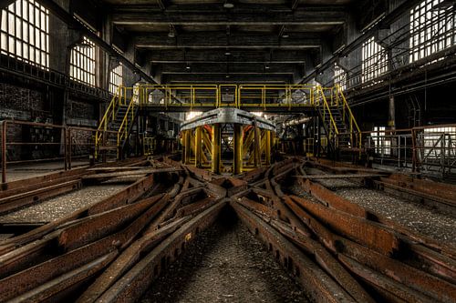 Symmetrische rails met lichtval in verlaten fabriek