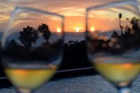 Proostende wijnglazen met zonsondergang boven de zee en zwembad