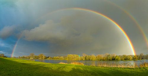 Regenboog tijdens een herfstbui boven de IJssel