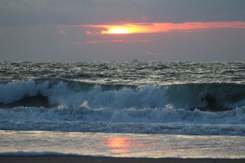 Omslaande golf voor ondergaande zon