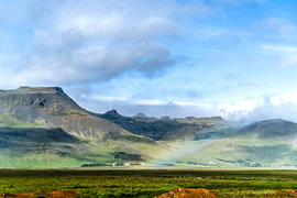 L'Islande : un paysage raffiné avec des montagnes verdoyantes, un ciel bleu et un arc-en-ciel sur Jan Willem de Groot Photography