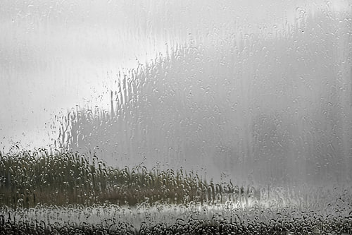 Blick durch eine regennasse Fensterscheibe – Starkregen prasse