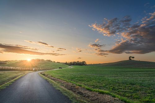 Landschap bij zonsondergang in de Maremma. Weg en glooiende heuvels