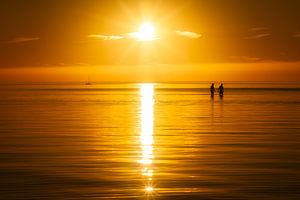 Ein sommerlicher Sonnenuntergang mit zwei Menschen im Wasser