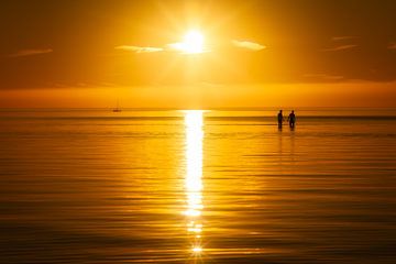 Ein sommerlicher Sonnenuntergang mit zwei Menschen im Wasser