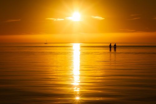 Een zomerse zonsondergang met twee mensen in het water