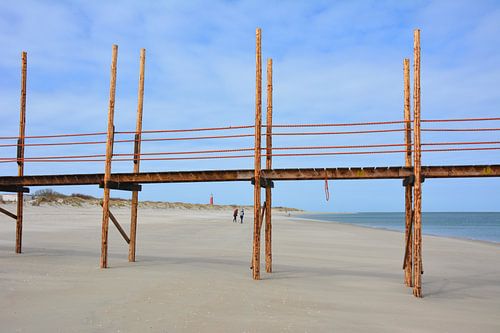 Houten pier voor veerboot Vlieland op strand Texel bij laag tij