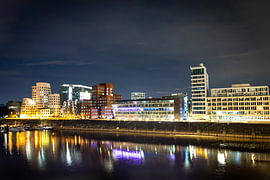Medienhafen Düsseldorf bei Nacht mit Gehry-Bauten und beleuchtetem Hafenbecken / Marina von Your Happy Life
