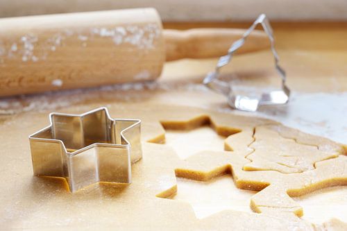 Backen zu Weihnachten, ausgerollter Teig mit Ausstechformen in Stern- und Tannenbaumform für traditi