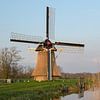 De oudkerkerkermolen in het avondlicht, met Aldtsjerk op de achtergrond van Tim Groeneveld