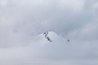 Besneeuwde bergtop in de wolken