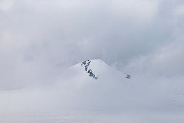 Besneeuwde bergtop in de wolken van Jani Moerlands