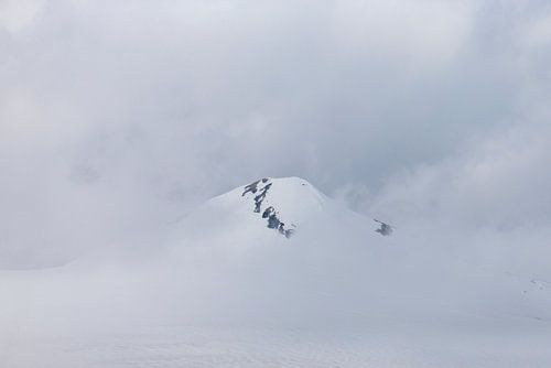 Besneeuwde bergtop in de wolken